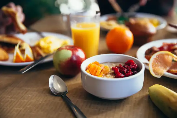 Colazione pre workout: porridge con frutta secca, succo d'arancia, mela e banana. Energia per iniziare la giornata!