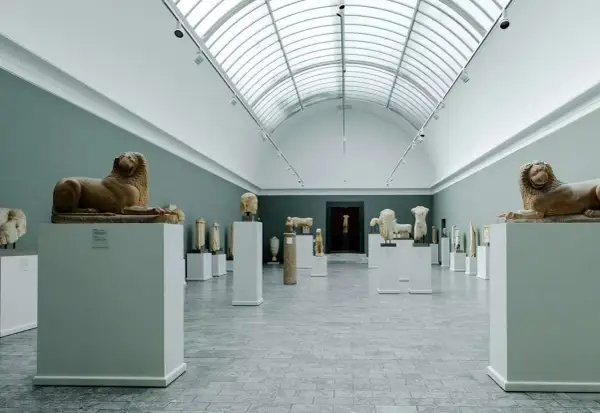 Ancient sculptures, including lion statues, are displayed in a grand hall, showcasing the impressive collection of Copenhagen art galleries.