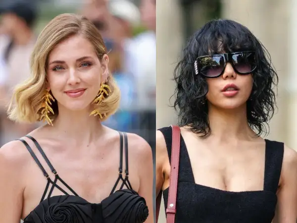Dwie kobiety w czarnych kreacjach. Jedna z blond włosami w stylu italian bob, druga z ciemnymi, kręconymi włosami i okularami.