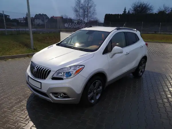 Biały Buick Encore stoi na mokrej, brukowanej nawierzchni.