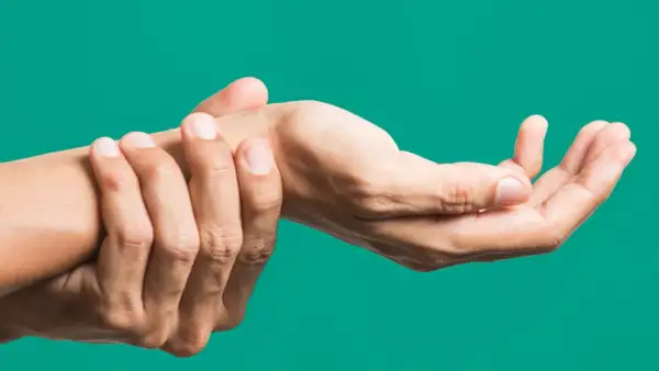 Mano che si tiene il polso, indicando dolore o fastidio, forse legato all'artrite polso.