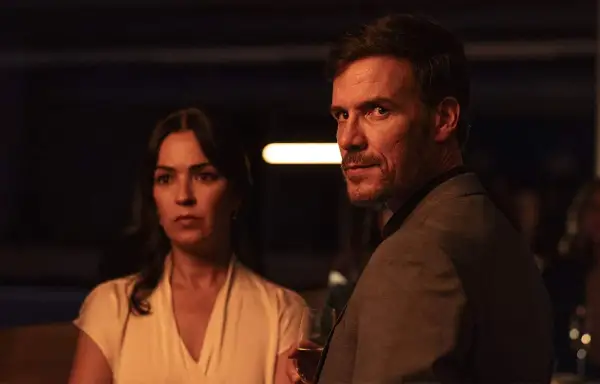 Man och kvinna i mörkt rum, en del av en psykologisk thriller topplista film. Mannen håller ett glas.