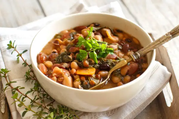 Una ciotola di fagioli misti, verdure e carote, guarnita con prezzemolo fresco. Perfetta per la cottura fagioli secchi.