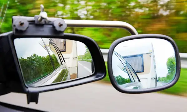 Zwei Spiegel zeigen die Straße und einen Wohnwagen. Für sicheres Fahren mit Anhänger ist der Wohnwagenspiegel Pflicht.