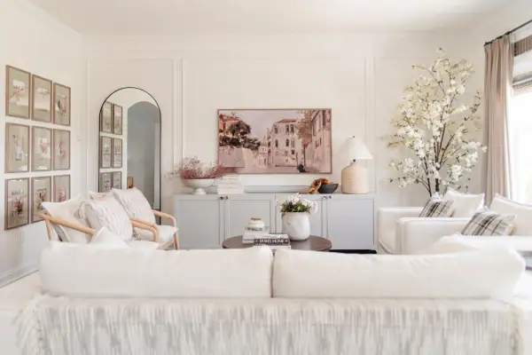 Elegant living room with a Venetian canal painting above a gray credenza. The walls feature decorative molding, adding a classic touch.