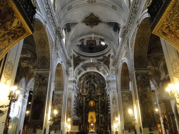 Interior de la iglesia de la Magdalena, con bóvedas ornamentadas, arcos y un retablo dorado.