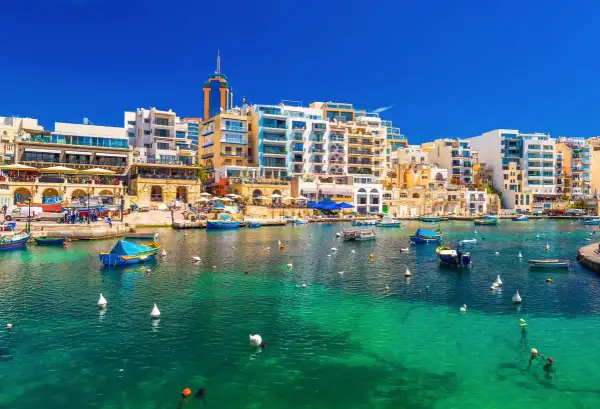 Malta, St Julian's: malowniczy port z turkusową wodą, łodziami i nowoczesnymi budynkami.