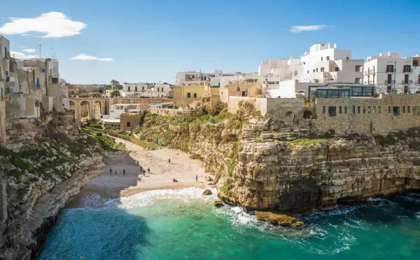 Un'idea per il tuo itinerario Puglia 7 giorni in macchina: la costa rocciosa di Polignano a Mare con la sua spiaggia e le case bianche a picco sul mare.