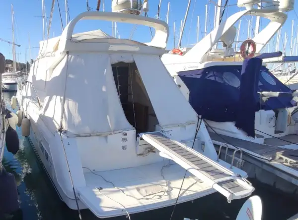 Il Raffaelli Typhoon, un lussuoso yacht bianco, è ormeggiato in un porto. La passerella è estesa, pronta per l'imbarco.