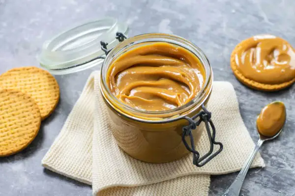 Un vasetto pieno di cremoso dulce de leche, pronto per essere spalmato su biscotti croccanti.