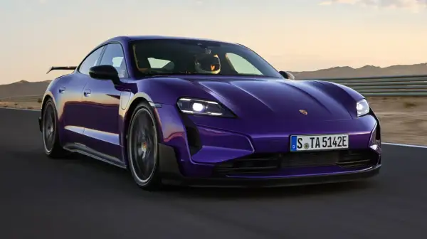 Fioletowy Porsche Taycan na torze wyścigowym. Kierowca w kasku. Sprawdź, jaka jest porsche taycan cena.