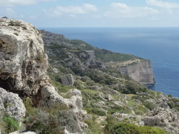 Malta's dramatic Dingli Cliffs, a rugged coastline meeting the deep blue sea under a cloudy sky.