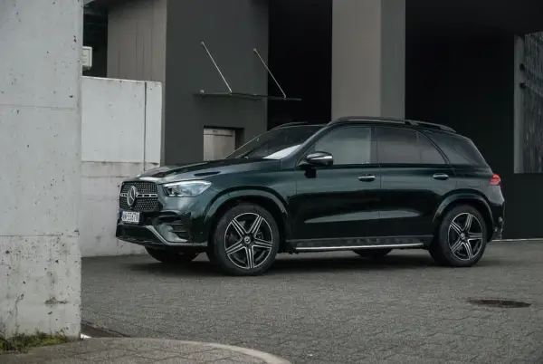 Ciemnozielony Mercedes GLE 350 stoi przed nowoczesnym budynkiem.