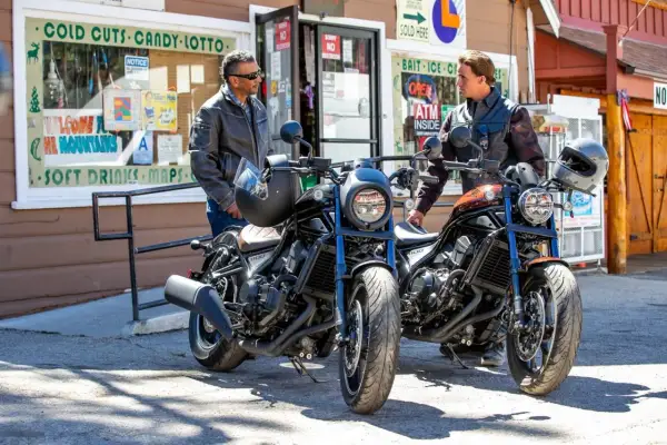 Dwóch mężczyzn w kurtkach stoi obok dwóch motocykli Honda CMX. Jeden motocykl jest czarny, drugi w kolorze miedzianym.