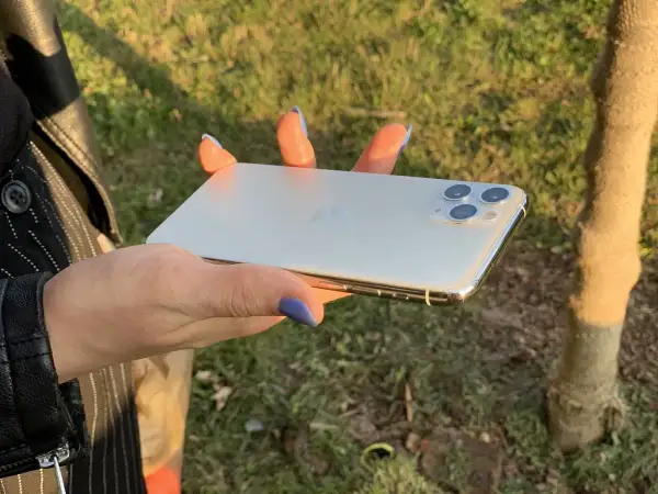 Dłoń trzyma biały iPhone 11. Wymiary telefonu idealnie pasują do dłoni, co widać na zdjęciu.