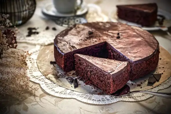 Ein saftiger schokokuchen mit glänzender Glasur, ein Stück wurde bereits herausgeschnitten.