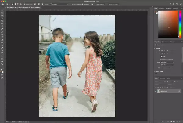 Two children, a boy and a girl, are walking away from the camera. The image is being edited in Photoshop, with a selection tool active, indicating a cut out process.