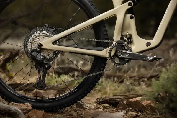 Tylna przerzutka i kaseta napędu rowerowego Shimano Deore LX na piaskowym fullu, gotowe na terenowe wyzwania.