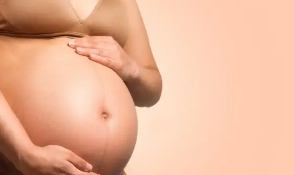 Brzuch ciężarnej kobiety, która zastanawia się, ile wytrzyma dziecko bez wód płodowych.