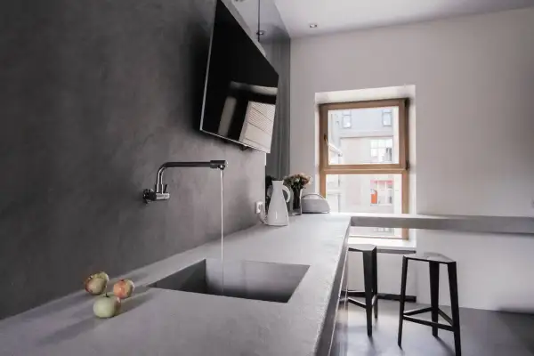 Encimera de cocina moderna con fregadero integrado de microcemento. Grifo cromado y tres manzanas sobre la superficie.