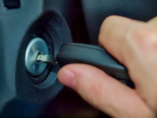 Main d'une personne insérant une clé dans le Neiman d'une voiture. Le prix du changement de Neiman est une préoccupation courante.