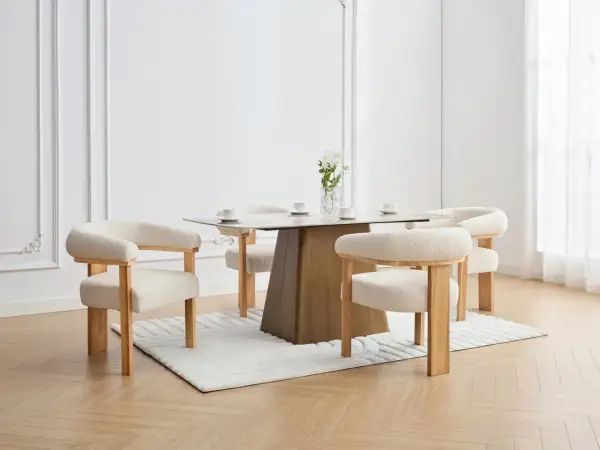 En elegant matplats med olika stolar runt ett modernt matbord. En vas med blommor står på bordet.