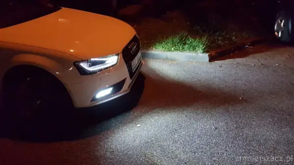 Białe Audi A4 B8 po lifcie z zapalonymi światłami przeciwmgielnymi. Wymiana żarówki przeciwmgielnej zakończona sukcesem.