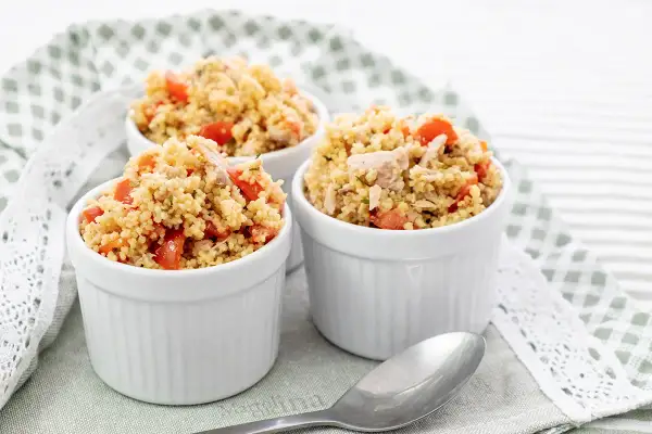 Tre coppette bianche piene di cous cous tonno e pomodorini, un piatto fresco e colorato.
