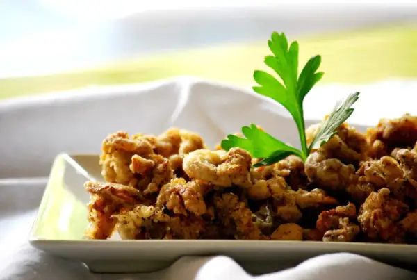 Camagroc crujiente en un plato blanco, decorado con perejil fresco. ¡Un bocado delicioso!