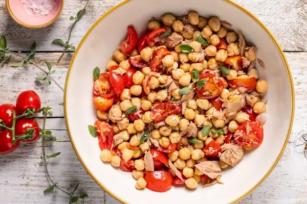Un'insalata di ceci estiva con pomodorini freschi e tonno, guarnita con erbe aromatiche. Perfetta per un pasto leggero e gustoso.
