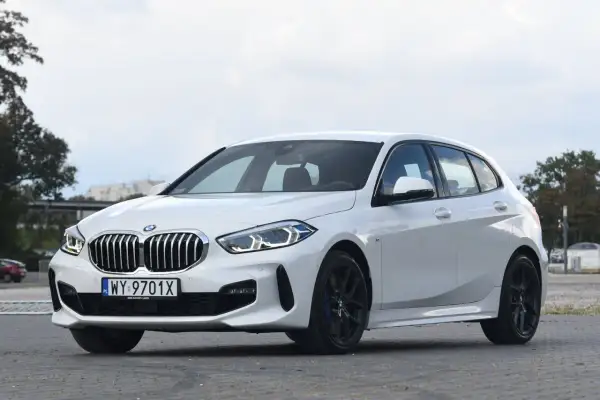 Białe BMW 118d z czarnymi felgami stoi na parkingu.