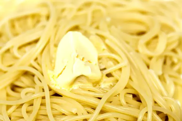 Spaghetti fumanti con una generosa porzione di burro che si scioglie, un classico piatto di pasta in bianco.