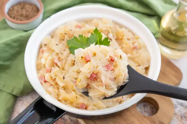 Sauerkraut kochen nach Omas Rezept: herzhaftes Gericht mit Speck und Kümmel, garniert mit Petersilie.