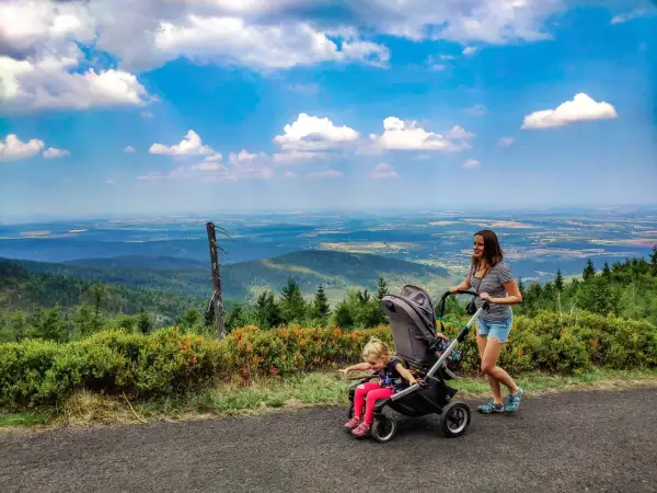 Mama z córką na spacerze, gdzie w góry z wózkiem. Piękny widok na dolinę i chmury.