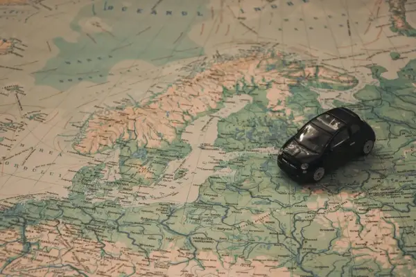 Czarny model samochodu na mapie Europy, sugerujący podróż 1000 km samochodem.