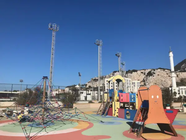 Parque infantil colorido con el Peñón de Gibraltar al fondo. ¡Un lugar ideal que hacer en Gibraltar con niños!