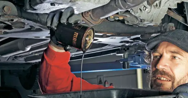 Mechanik wymienia stary olej silnikowy. Pamiętaj, co ile się wymienia olej, by auto służyło latami.