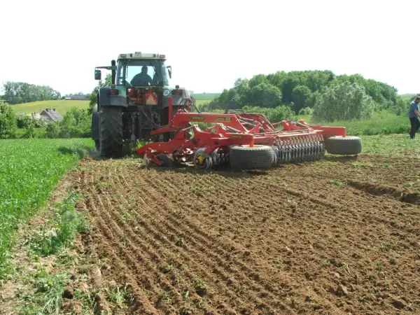 Traktor z agregatem uprawowym wykonuje podorywkę na polu.