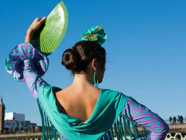 Bailarina de flamenco con abanico verde, evocando el flamenco origine. Su vestido vibrante y flor en el pelo resaltan la pasión.