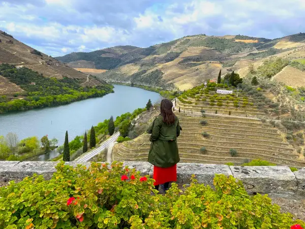 Mujer admira la impresionante **ruta del Duero**, con sus viñedos en terrazas y el río serpenteando entre colinas verdes.