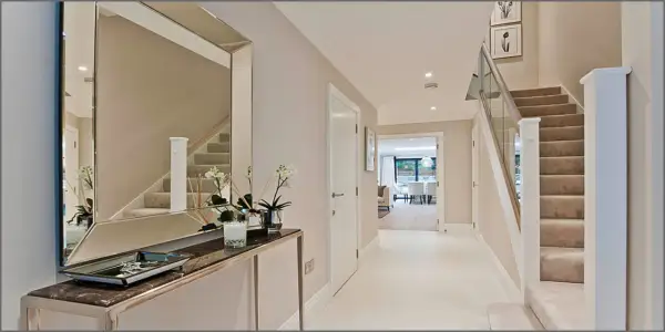 Ingresso moderno con specchio, consolle, scale e porta aperta su un'altra stanza.
