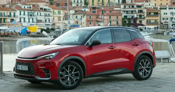 Czerwony Lexus LBX na tle nadmorskiego miasteczka. Sprawdź, jaka jest lexus lbx cena i zacznij planować wakacje!