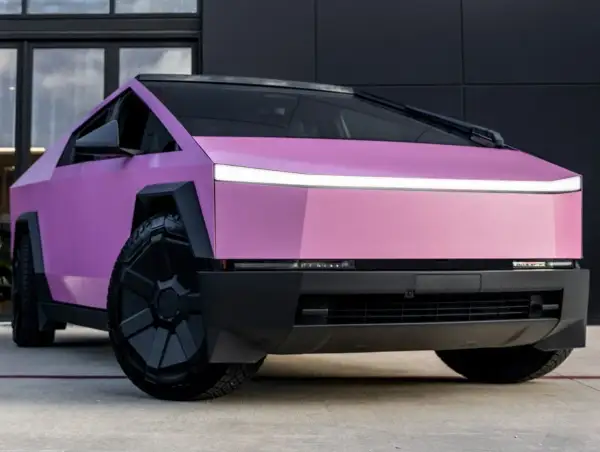 Różowy CyberTruck z futurystycznym designem i masywnymi kołami.