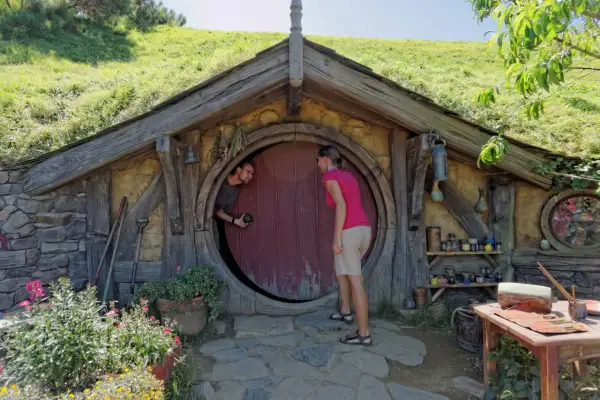 Para w Hobbiton w Nowej Zelandii pozuje przed okrągłymi drzwiami.