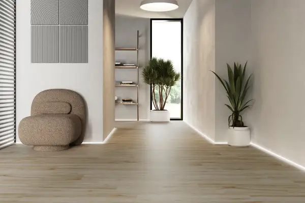 Ljus hall med klinker som ser ut som trägolv. En unik fåtölj och gröna växter skapar en inbjudande atmosfär.