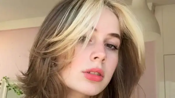 Dziewczyna z modnym wolf cut bez grzywki, z pasemkami blond na ciemniejszych włosach.