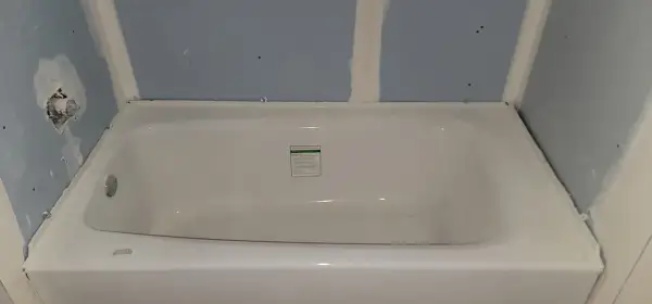 Installing cement board around a tub is underway. The tub is in place, and the blue drywall is being prepped for the next steps.