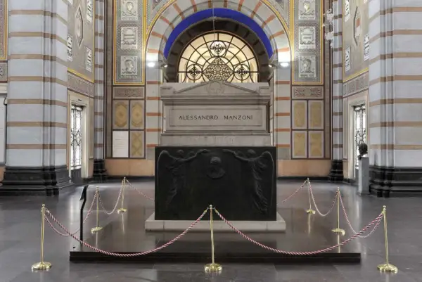 La tomba di Manzoni, imponente monumento con bassorilievi di angeli e ritratto, è protetta da cordoni dorati.