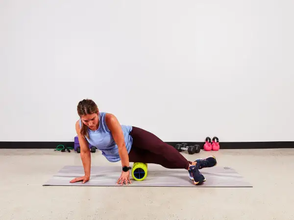 Donna usa un foam roller per alleviare la bandelletta ileotibiale. Soluzioni per il recupero muscolare.