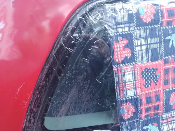 Czerwony lakier samochodu z folią ochronną i kolorową tkaniną z motywem zwierząt. To dowód, że lakierowanie samochodu zrób to sam może być kreatywne.